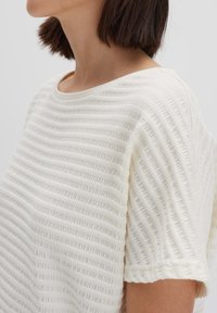 Witte top met korte mouwen, gemaakt van gestructureerde stof met verticale strepen. Heeft een ronde halslijn en een losse pasvorm, die de zachtheid en het comfort benadrukt.