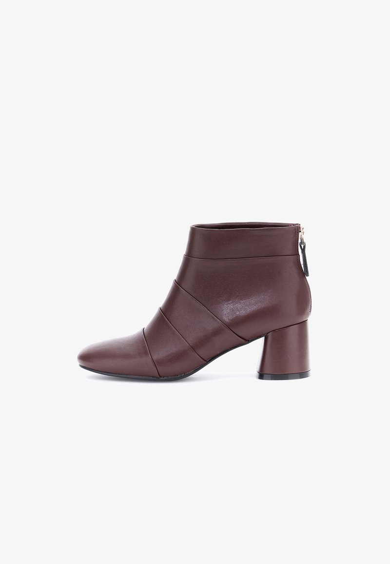 Bottines en cuir marron avec un bout pointu, présentant des plis horizontaux et un talon bloc. Fermeture éclair à l'arrière avec un tirant décoratif.