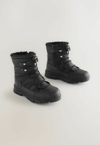 Bottes d'hiver noires avec une tige en tissu texturé, doublure en fausse fourrure, bandes élastiques et fermeture éclair latérale. Semelle en caoutchouc robuste pour une bonne traction.