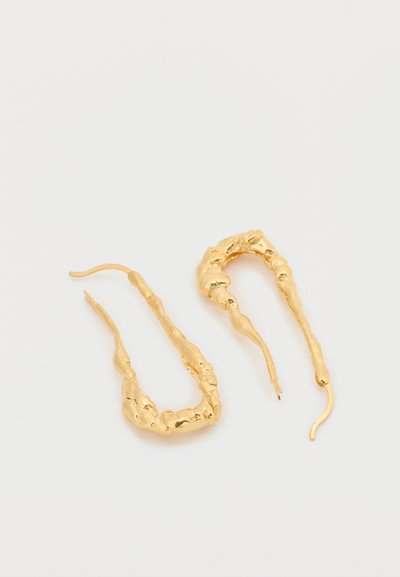 Náušnice zo zlatého kovu s nepravidelným, organickým tvarom, s textúrovaným povrchom a predĺženým háčikovým dizajnom.
