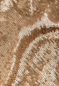 Goldfarbener Paillettenstoff mit schimmernder Oberfläche, der sich durch überlappende, kreisförmige Pailletten auszeichnet, die ein strukturiertes, reflektierendes Muster erzeugen.