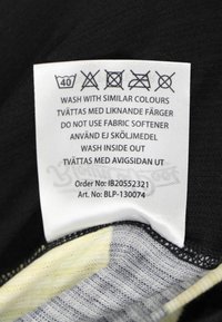 Black fabric tag with washing instructions in multiple languages; features care symbols and order details; smooth texture, rectangular shape.