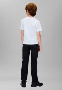 Camiseta blanca de manga corta combinada con jeans negros. El conjunto presenta un diseño sencillo con un corte recto y colores sólidos.