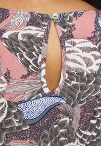 Short-sleeve garment featuring a pink fabric with intricate bird and floral patterns. Notable button at the nape with a keyhole cutout.