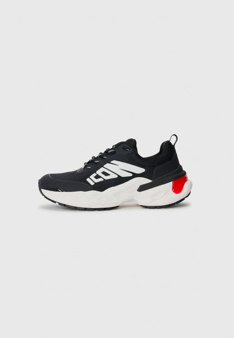 Black athletic shoe with a textured upper, white logo accent, cushioned sole in white and black, and a red detail on the heel.