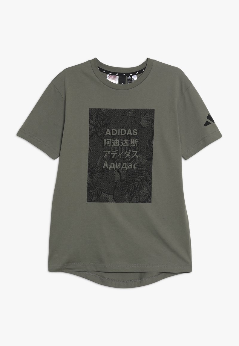 Olivi vihreä lyhythihainen t-paita, joka on valmistettu puuvillasta. Etupuolella on suuri musta kukkagraafi, jossa on "ADIDAS"-teksti useilla kielillä.