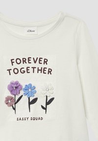 Witte katoenen blouse met lange mouwen, versierd met bloemenapplicaties in paars, blauw en wit, met de teksten "FOREVER TOGETHER" en "SASSY SQUAD" in bruin.