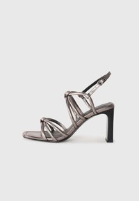 Metallic brons högklackad sandal med design av flera remmar, öppen tå, ankelrem med spänne och fyrkantig klack. Slät textur.