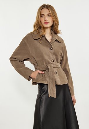 Giacca in suede marrone con colletto, chiusura a bottoni e cintura coordinata. Abbinata a una gonna in satin nera, che mostra una texture liscia.
