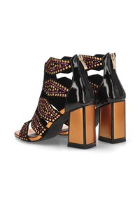 Sandalias de tacón alto de charol negro con acentos de tachuelas multicolores, un diseño de cortes geométricos y un tacón cuadrado grueso.