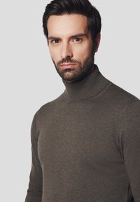 Brązowy, prążkowany sweter w serek z długimi rękawami, o dopasowanym kroju i miękkiej strukturze, umieszczony na neutralnym tle.