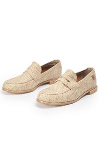 Mocasines beige tejidos con una superficie texturizada, que presentan una puntera redondeada, una cinta decorativa a lo largo del empeine y una suela de goma marrón claro.