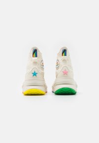 Sneakers with cream speckled upper, colorful star accents in blue, pink, and green, and a patterned sole in bright colors.