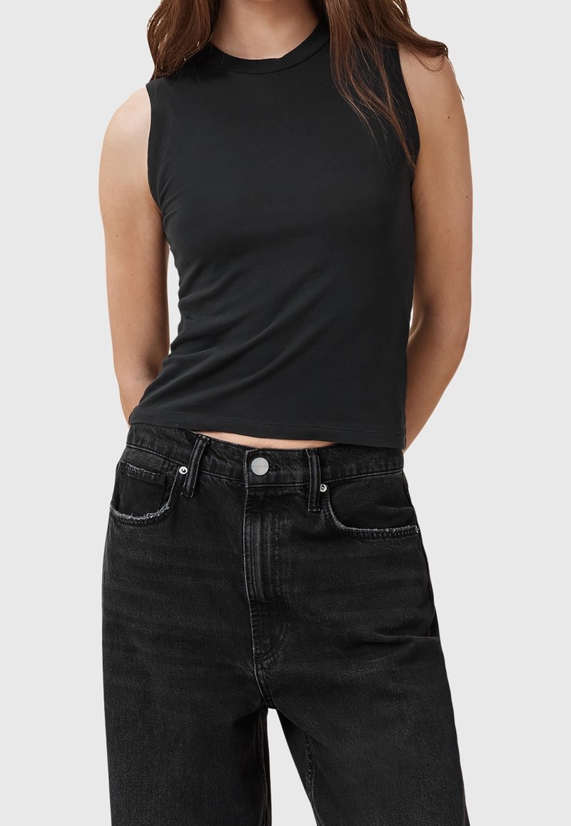 Top senza maniche nero con scollo tondo, realizzato in tessuto leggero; abbinato a jeans in denim scuro a vita alta con tasche frontali.
