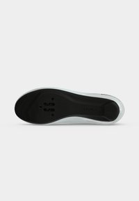 Semelle blanche de chaussure de vélo avec zone de fixation de la cale noire et trois trous pour vis de fixation de la pédale.