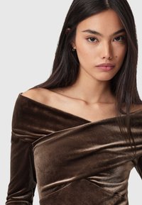 Fløjls-top med bar skulder i dybbrun, med et krydset frontdesign og diskret glans, der fremhæver en blød tekstur og draperingseffekt.