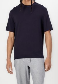 T-shirt bleu marine à manches courtes en coton doux, doté d'un col rond et de poignets côtelés, associé à un pantalon gris rayé.