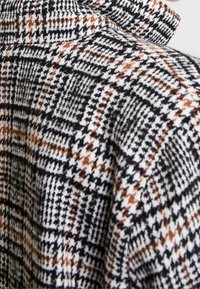 Sako z vlněné směsi s kostkovaným vzorem v černé, bílé a hnědé barvě, se strukturovaným límcem a texturovaným povrchem.