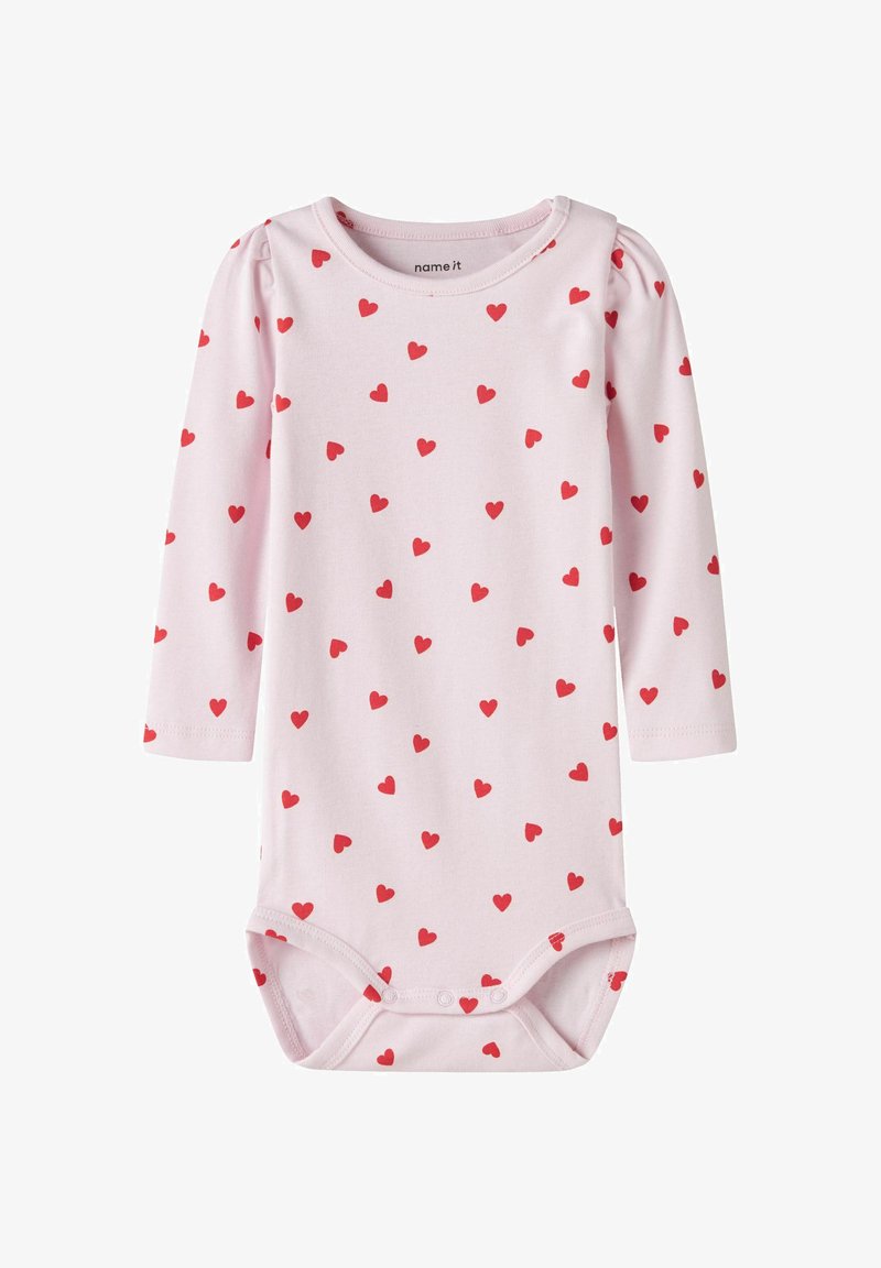 Lichtroze babyromper met lange mouwen, bedekt met een rode hartprint, drukknoopsluiting bij de kruisnaad en een afgeronde halslijn.
