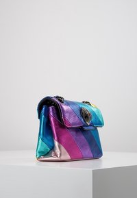 Vícebarevná kabelka s metalickým povrchem a pruhy v modré, růžové a fialové barvě. Obsahuje klopu se zavíráním a řetízkový popruh.