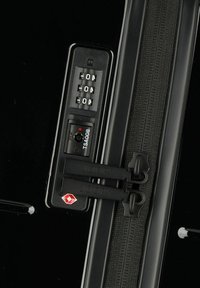 Valigia rigida nera con lucchetto a combinazione, doppie cerniere contrassegnate "JOOP!" e indicatore del lucchetto TSA. Texture liscia e finitura lucida.