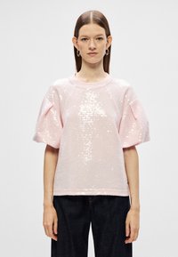 Roosa sädelustritega ülemine osa lühikeste puhvärvidega ja ümmarguse kaelusega, mis paistab silma tekstuurse kanga ja lõdva lõikega.