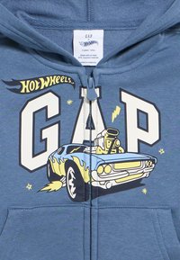 Mėlynas mažylio džemperis su GAP ir Hot Wheels logotipais bei geltono ir mėlyno „muscle“ automobilio su liepsnomis ir žaibo blyksniais grafika.