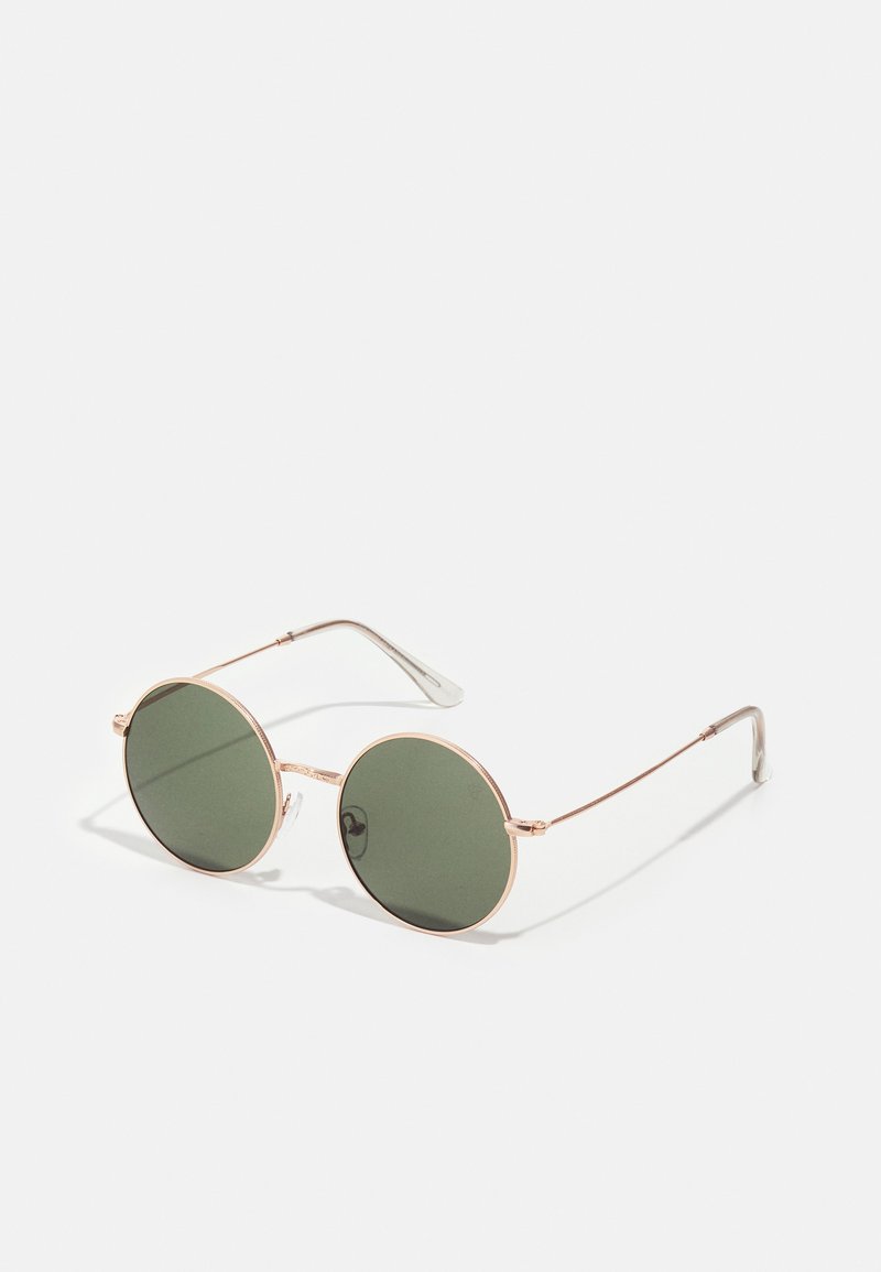 Kulaté sluneční brýle se zelenými čočkami, tenkými zlatými kovovými rámy a průhlednými konci nožiček. Minimalistický design s hladkým povrchem.