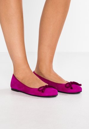 Fuchsia ruskindsballetsko med rundede tæer, prydet med en knyttet detalje foran og en flad sort sål.