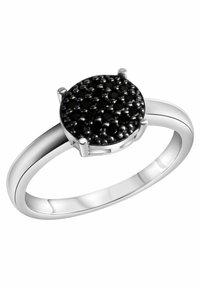 Anello in argento con una parte superiore in pietra nera rotonda e testurizzata, circondata da piccoli dettagli neri, con una fascia lucida e quattro montature a griffe.