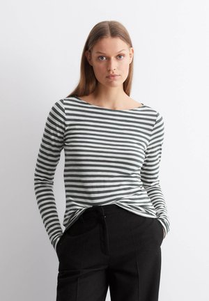 Chemise à manches longues rayée en gris et blanc. Tissu doux avec un col bateau et une coupe décontractée, associée à un pantalon noir.