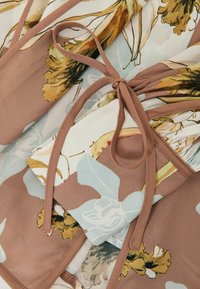 Lilleline mähkkleit helesinise ja kreemika mustriga, millel on pruunid aktsendid, valmistatud kergest kangast. Vöökoht on reguleeritav lipsuga.