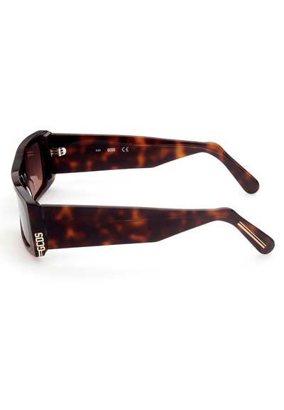 Occhiali da sole tortoise marrone con montatura geometrica, aste spesse e dettagli in oro vicino alle tempie. Le lenti sono scure e rettangolari.