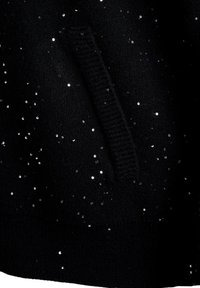 Černý svetr s rozptýlenými stříbrnými flitry, texturovanou pleteninou a žebrovanou kapsou. Měkký, útulný materiál.