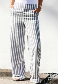 Pantalon large à rayures avec une taille élastique haute, présentant des rayures grises et blanches alternées, et des poches latérales. Fabriqué en tissu léger.