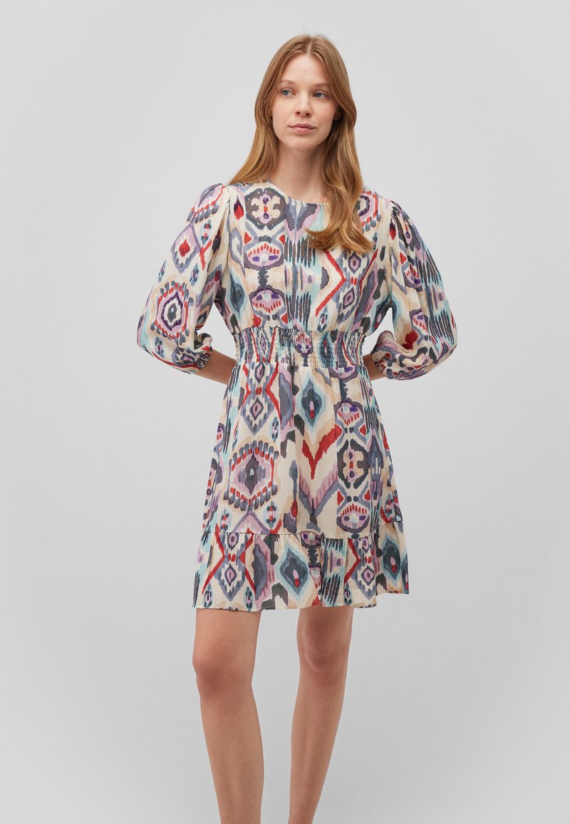 Druckkleid mit taillierter Taille, Puffärmeln und einem volantrichten Saum. Das Muster umfasst geometrische Formen in sanften und lebhaften Farben.