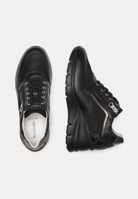 Des baskets noires avec un mélange de matériaux en cuir et en maille, dotées d'un col rembourré, d'un laçage à l'avant et d'un détail en zip métallique sur le côté.