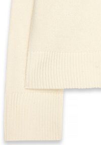 Pull en tricot couleur crème avec un ourlet et des poignets côtelés, tissu texturé avec un tissage lâche, mettant en avant des lignes épurées et une coupe décontractée.