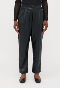 Pantalons en simili cuir noir avec une coupe décontractée, des plis avant, une taille élastique et une fermeture à un bouton. Assortis avec des chaussures plates noires.