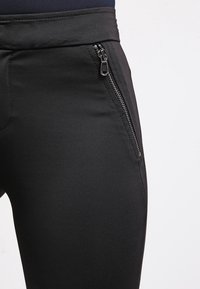 Svarta träningsbyxor i slät, elastisk tyg, utrustade med en zippered ficka på sidan och en bred midjeband för komfort.