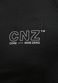 Tela negra que muestra un patrón texturizado con el logotipo impreso en blanco "CNZ™ CORE—NINE ZERO" destacado.