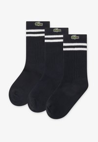 Τρία ζευγάρια σκούρες μπλε κάλτσες με ραβδωτή υφή. Κάθε ζευγάρι έχει δύο λευκές ρίγες στο πάνω μέρος και ένα κεντημένο πράσινο λογότυπο κροκοδείλου.