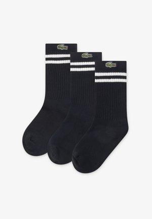 Τρία ζευγάρια σκούρες μπλε κάλτσες με ραβδωτή υφή. Κάθε ζευγάρι έχει δύο λευκές ρίγες στο πάνω μέρος και ένα κεντημένο πράσινο λογότυπο κροκοδείλου.