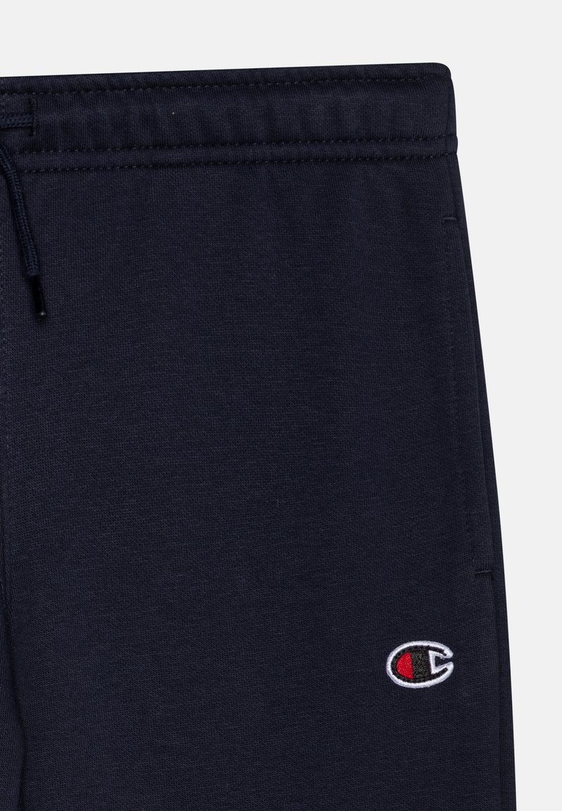 Pantalones de chándal azul marino hechos de tejido suave, con una cintura elástica y drawstring, y un pequeño logo bordado en blanco y rojo.