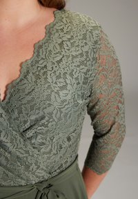Olivgrünes Wickelkleid mit aufwendigen Spitzenverzierungen, einem gewellten Ausschnitt und transparenten Spitzen-Dreiviertelärmeln. Taillenbindung.