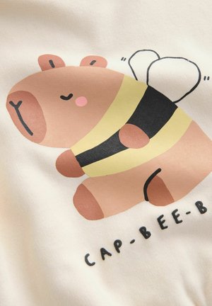 Joonistus pruunist multikakarust, kes kannab musta ja kollase triibulise mesilase kostüümi, millel on heledad roosad detailid, ning all on tekst "CAP-BEE-B".