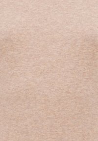 Jasnoróżowa bawełniana koszulka z gładką teksturą i prostym wzorem, z lekkim melanżowym wyglądem na całej powierzchni materiału.