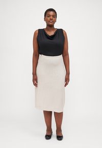 Svart cowl neck topp og kremhvit ribbet midiskjørt med rett snitt. Glatte stoffer med subtil tekstur; kombinert med svarte leiligheter.