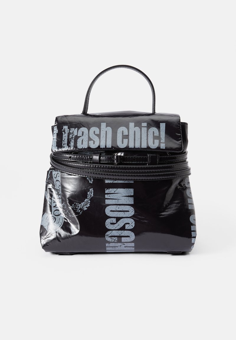 Musta reppu, joka on valmistettu kiiltävästä materiaalista, jossa on hopeatekstiä. Varustettu ylhäältä tulevalla kahvalla, vetoketjulla ja painettujen logotietojen yksityiskohdilla.