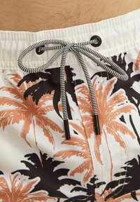 Costumi da bagno da uomo con una base bianca, caratterizzati da un motivo di palme arancioni e nere. Dotati di un cordoncino nero in vita.